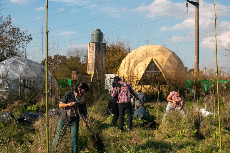 Minga de plantación en la agrofloresta con el domo geodésico de fondo